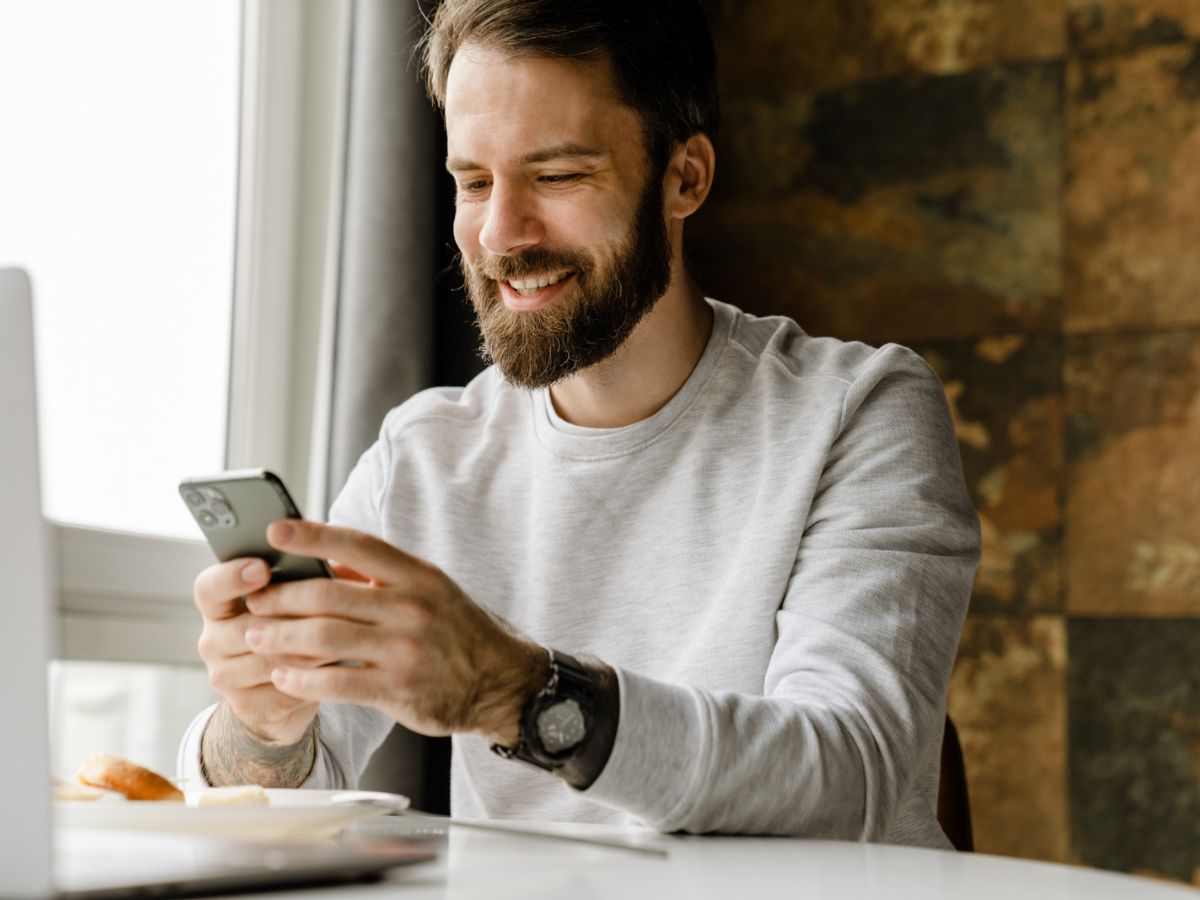 Man smiling while looking at his phone running Fongo Mobile app
