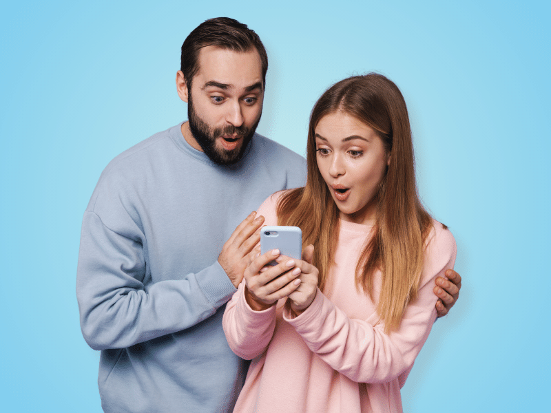 a couple looking at a cell phone with excitement